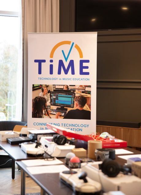 A banner reading 'TiME - Technology in Music Education' behind a table with various music tech equipment.