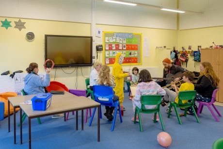 A group of children and adults sat in a circle in a classroom