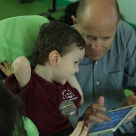 Smiling pupil with microphone and iPad, feeling vibrations from a speaker