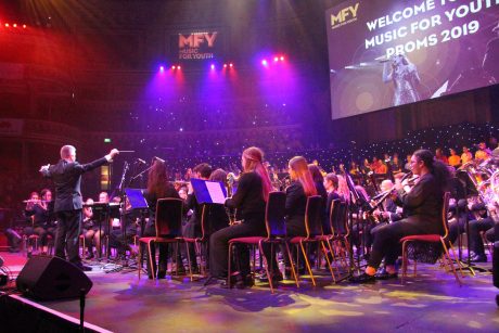 Peter Smalley conducting the County Youth Concert Band in the Royal Albert Hall, with purple lighting above