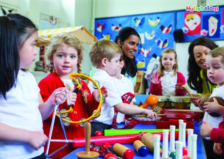 A group of young children playing various percussion instruments with teachers