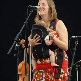 woman singing and holding baby in front.