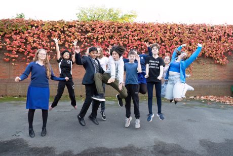 A group of children stood outside jumping in the air