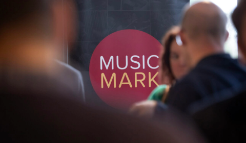music mark logo behind a crowd of people
