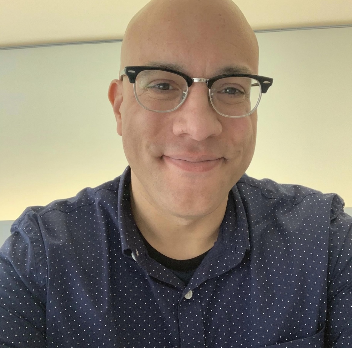 The image is of Tony Rideout, who is wearing a dark blue spotty shirt and glasses.
