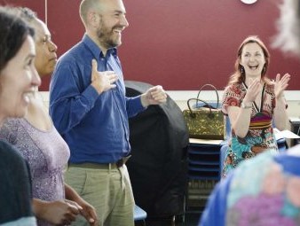 Man and woman laughing and clapping in group session in room