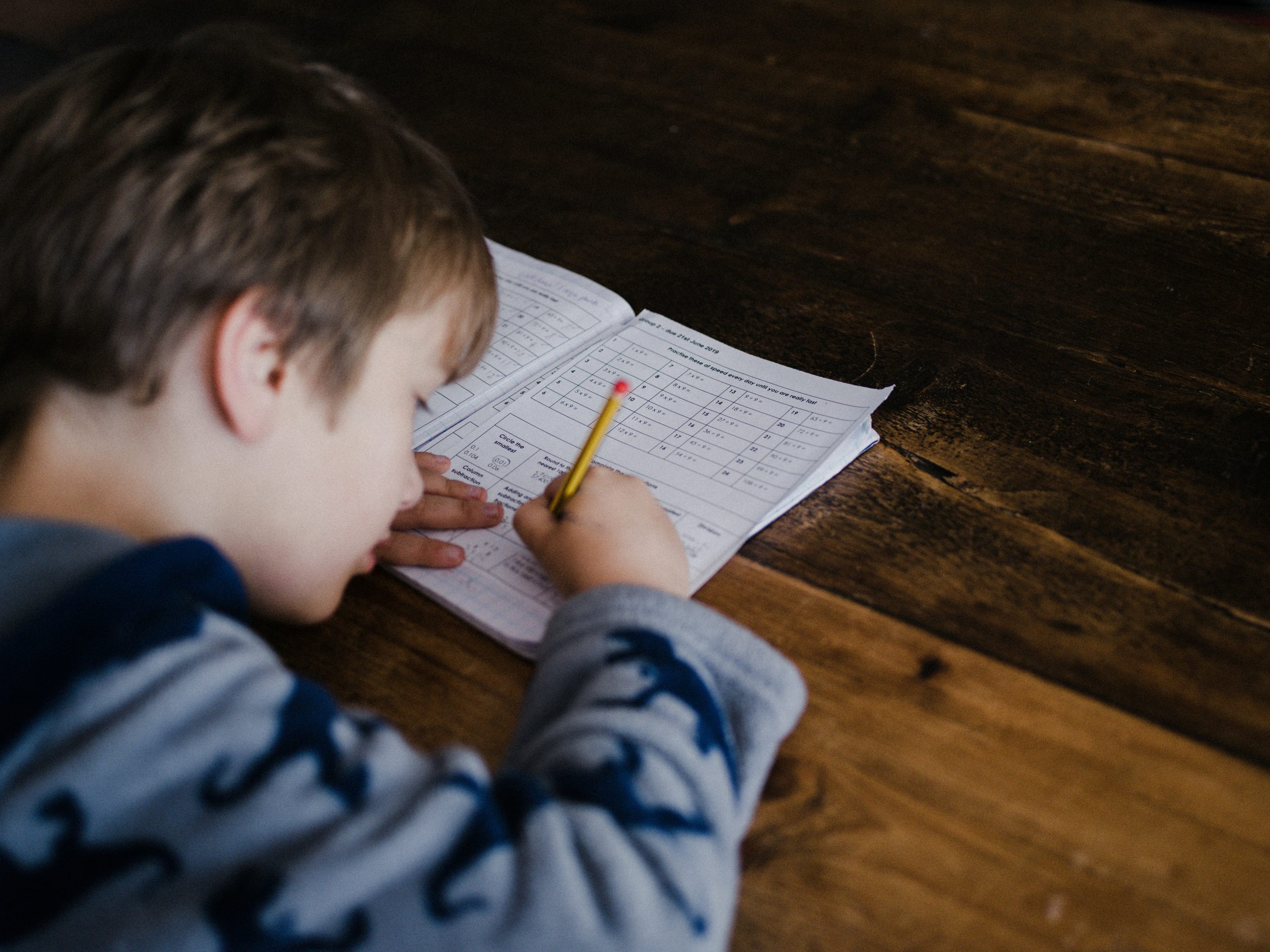 A child is doing a maths worksheet at a desk. 