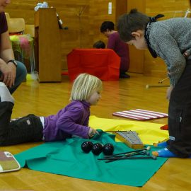 Two young children and an adult explore a xylophone together