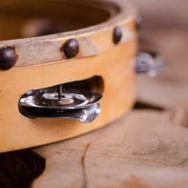 Edge of a tambourine on wooden surface.
